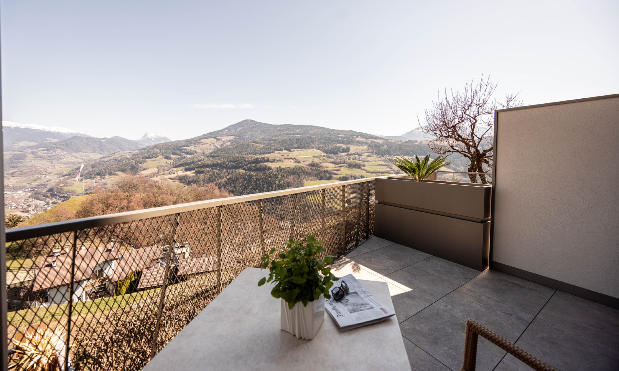Balkon mit Tisch und Stühlen und Blick auf die Dolomiten und ins Tal - Egger Apartments & Suites