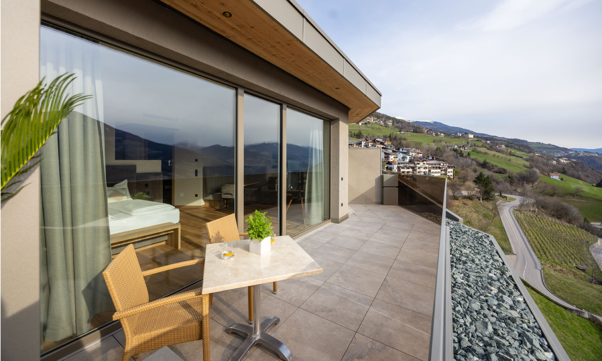 Terrasse mit Tisch und Stühlen und Blick auf die Dolomiten und ins Tal - Egger Apartments & Suites