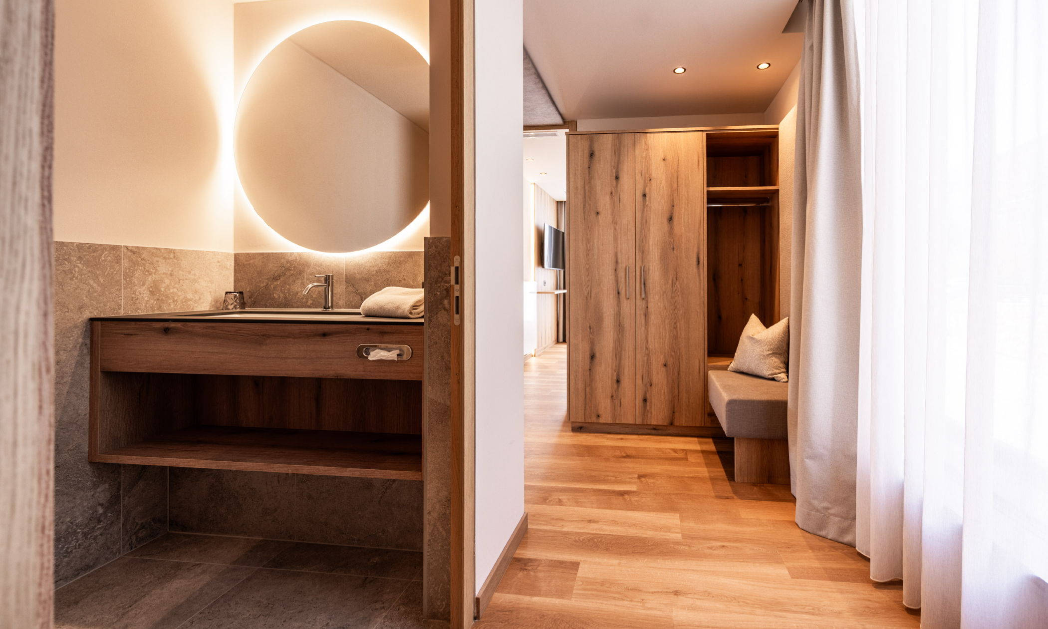 Eingang des Apartments mit Blick ins Bad auf das Waschbecken und mit Blick auf die Gardarobe - Egger Apartments & Suites