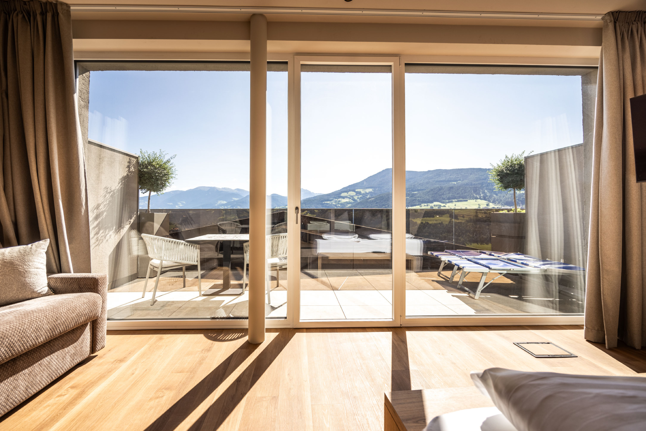 helle moderne Suite mit großen Fenstern und Blick ins Tal und auf die Berge