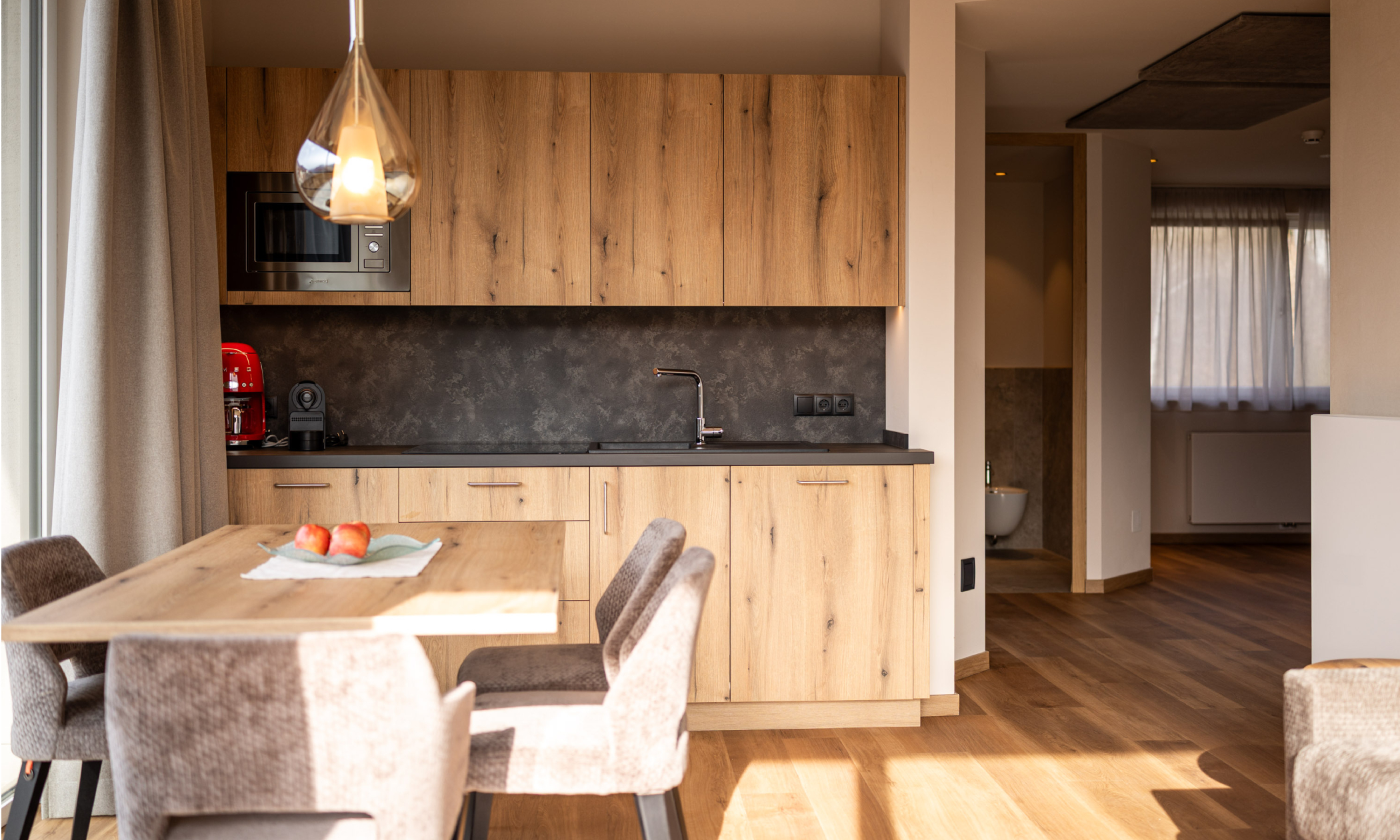 Wohnraum mit Blick auf die Küchenzeile und Esstisch - Egger Apartments & Suites