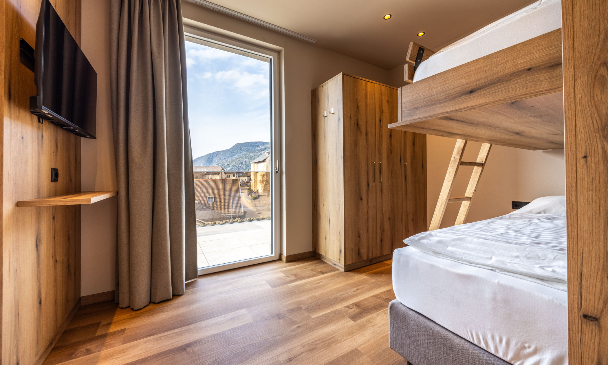 Schlafzimmer mit Etagenbetten und großem Fenster - Egger Apartments & Suites