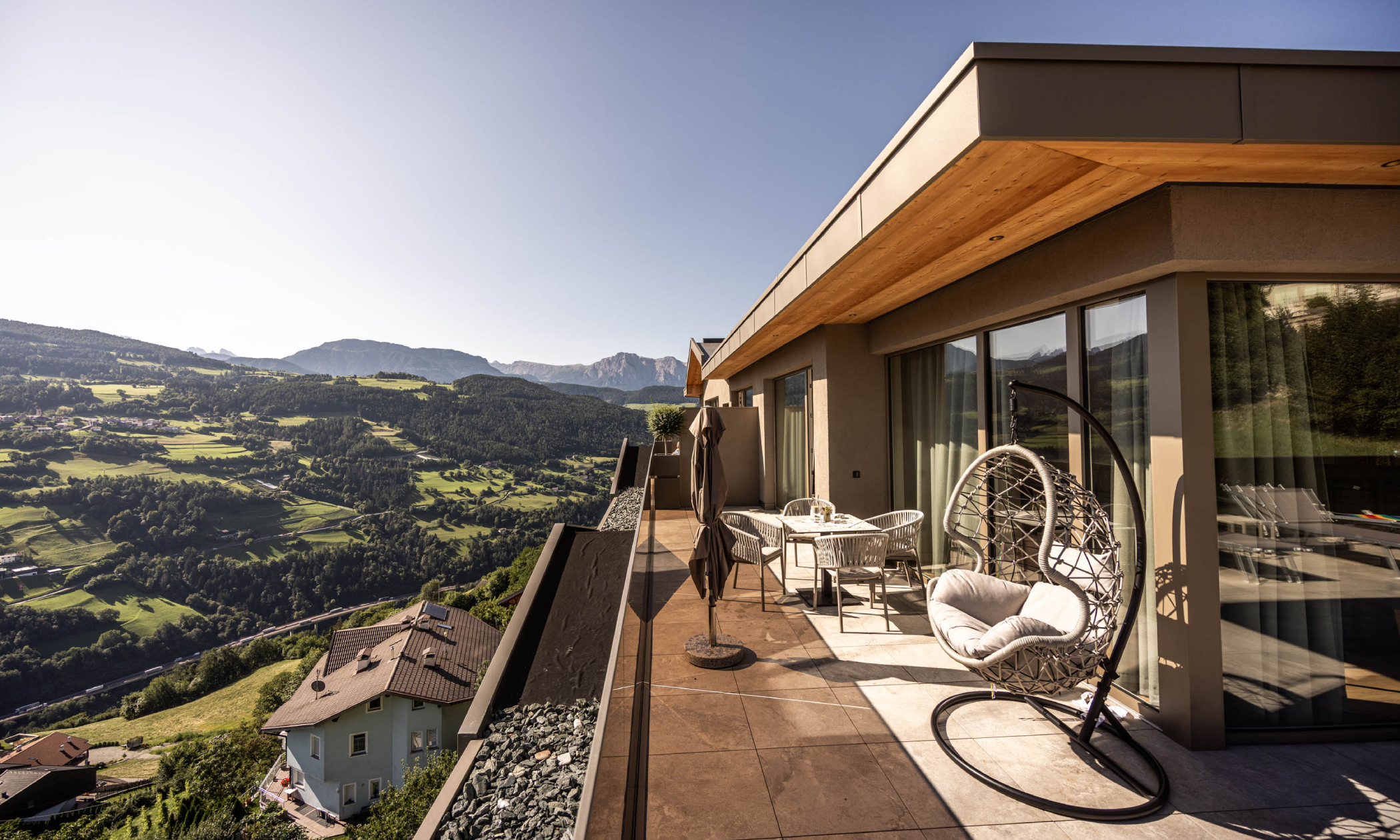 Terrasse mit Geländer aus Glas mit Ausblick ins Tal und auf die Dolomiten