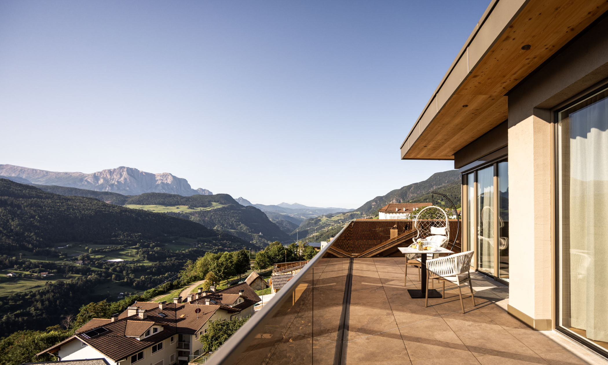 Terrasse mit Geländer aus Glas mit Ausblick ins Tal und auf die Dolomiten